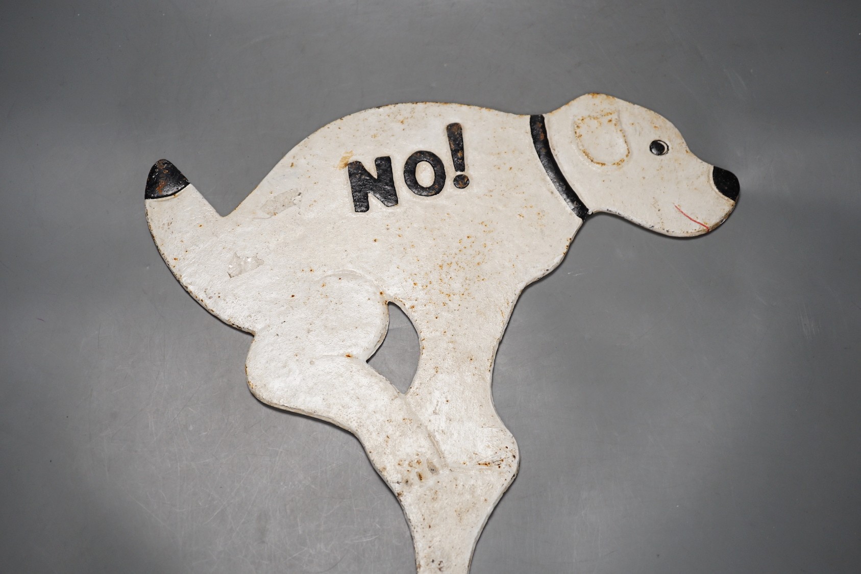 A 1950's novelty painted cast iron sign, in the form of a squatting dog